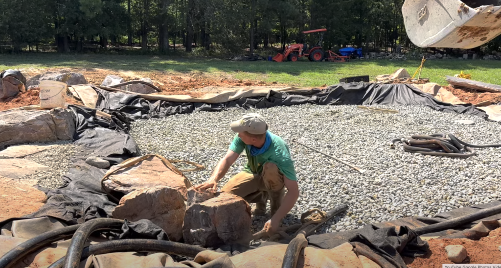 Adding first boulders next to plumbing for wetland filter
