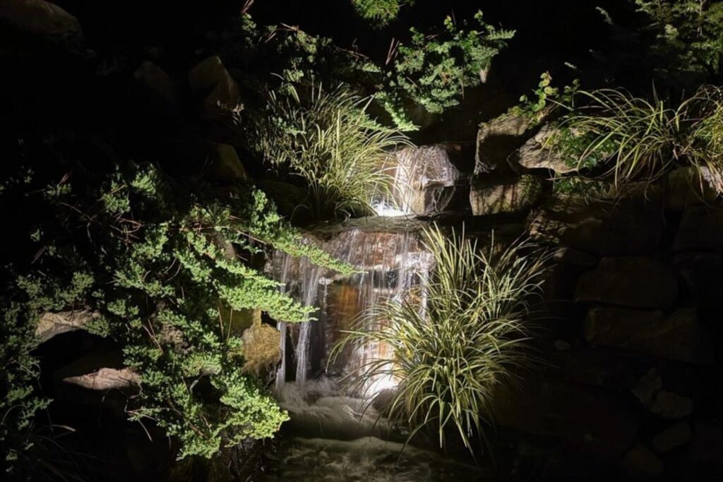 Beautiful custom-built waterfall glowing at night with underwater lighting by Pondscapes of Charlotte.
