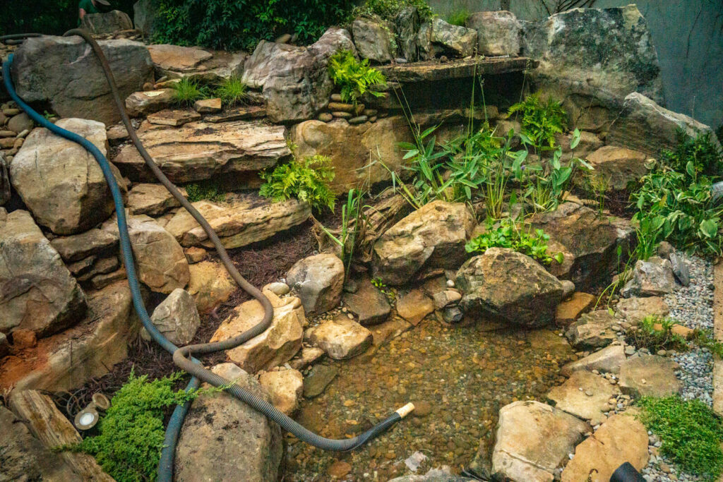 Three bubbling boulder water features being filled with water after installation in Charlotte landscape showing natural stone fountains