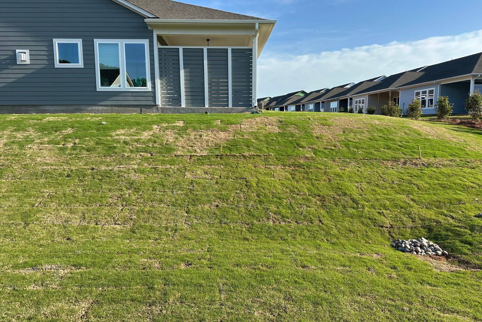 Grassy backyard hill before pond and waterfall construction in Encore at Streamside, Waxhaw, NC.