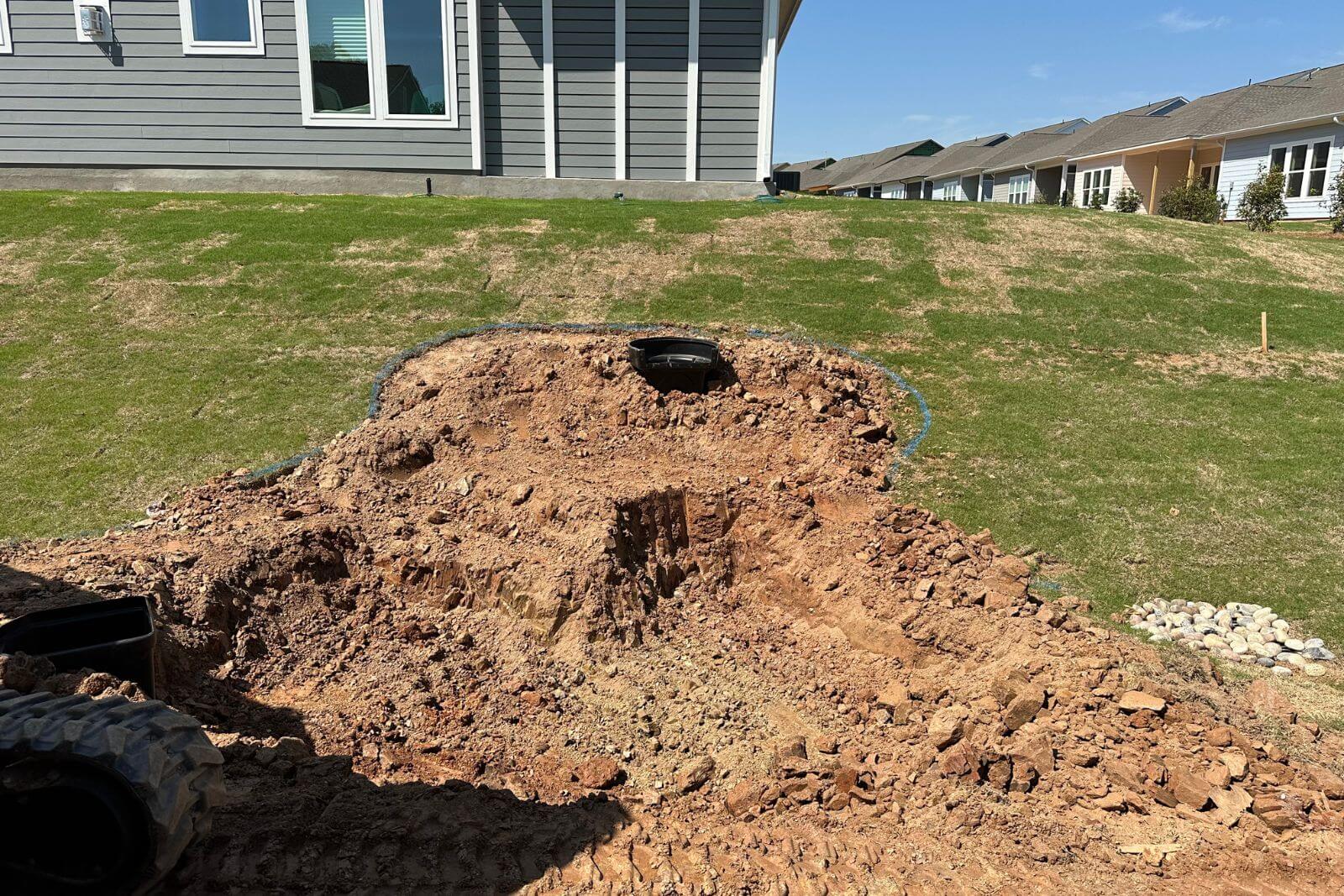 Pond construction in progress with grass removed and an Aquascape 2500 BioFalls installed at the top of the hill in Encore at Streamside, Waxhaw, NC.