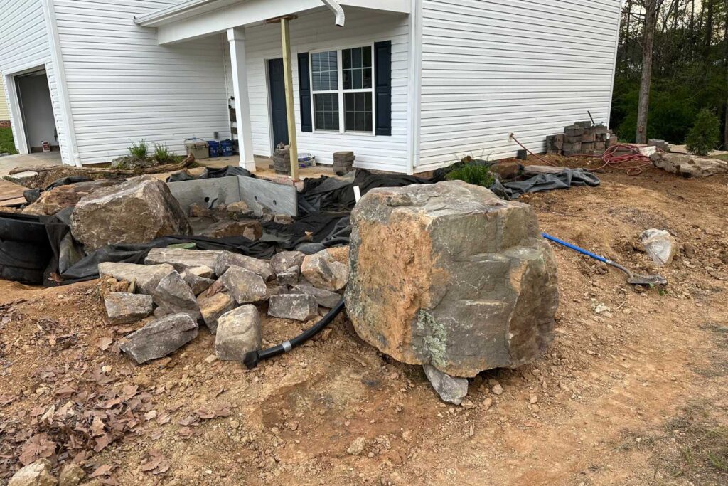 Large boulder being placed in koi pond during construction by Pondscapes of Charlotte in Wesley Chapel, North Carolina