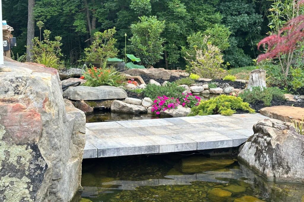 Floating paver bridge over a koi pond built by Pondscapes of Charlotte, award-winning pond builders in Wesley Chapel, North Carolina