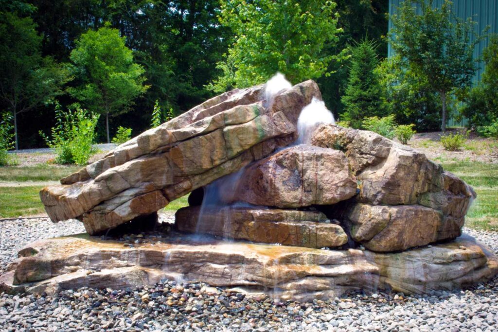 Three large bubbling boulders carefully set in place with an excavator, creating a bold and tranquil centerpiece in a custom water feature.