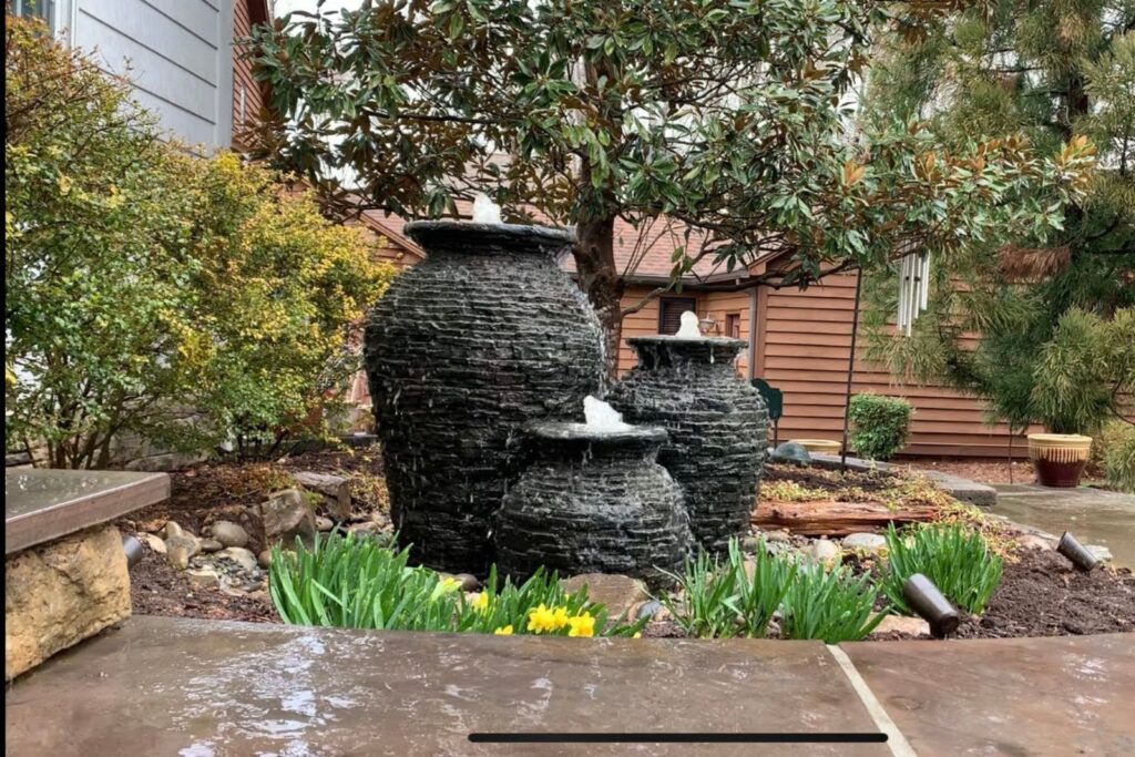 A custom water feature showcasing three Aquascape slate stacked urns, beautifully arranged to create a serene outdoor focal point.