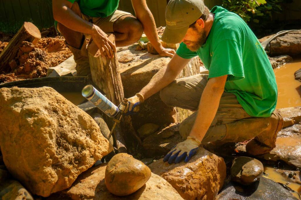 Braeden Branch is foaming a waterfall he is building with Pondscapes of Charlotte