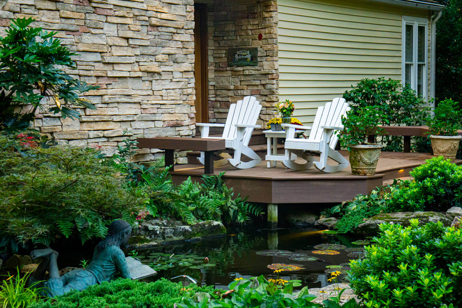 Backyard koi pond deck overlooking natural ecosystem waterfall with lily pads and aquatic plants in Charlotte, North Carolina