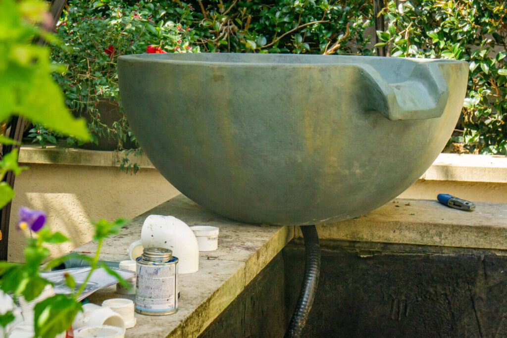 Nearly completed Aquascape spillway bowl installation showing natural stone integration and water flow design on South Park koi pond