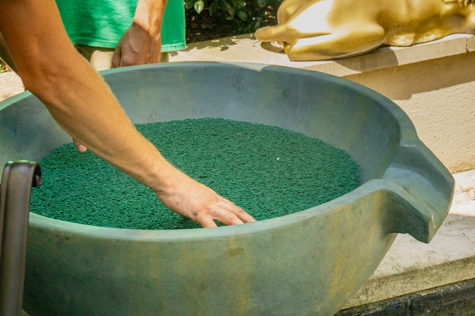 Professional pond technicians carefully positioning Aquascape spillway bowl during koi pond enhancement project in South Park, Charlotte