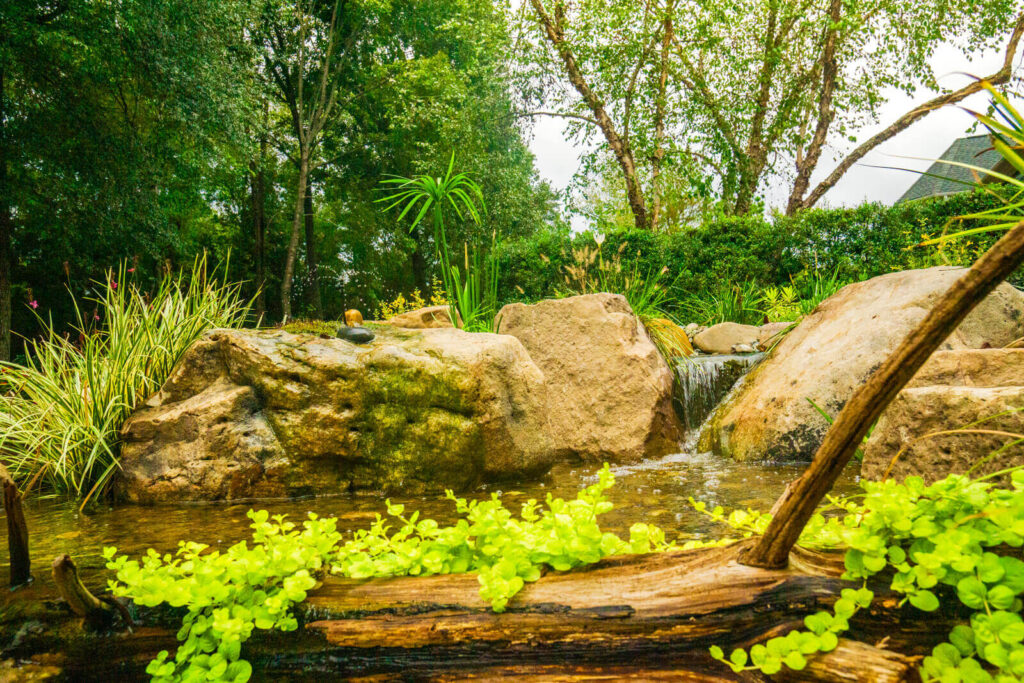 Small pondless waterfall stream with cedar log accent and natural stone in Marvin, North Carolina residential backyard for attracting birds