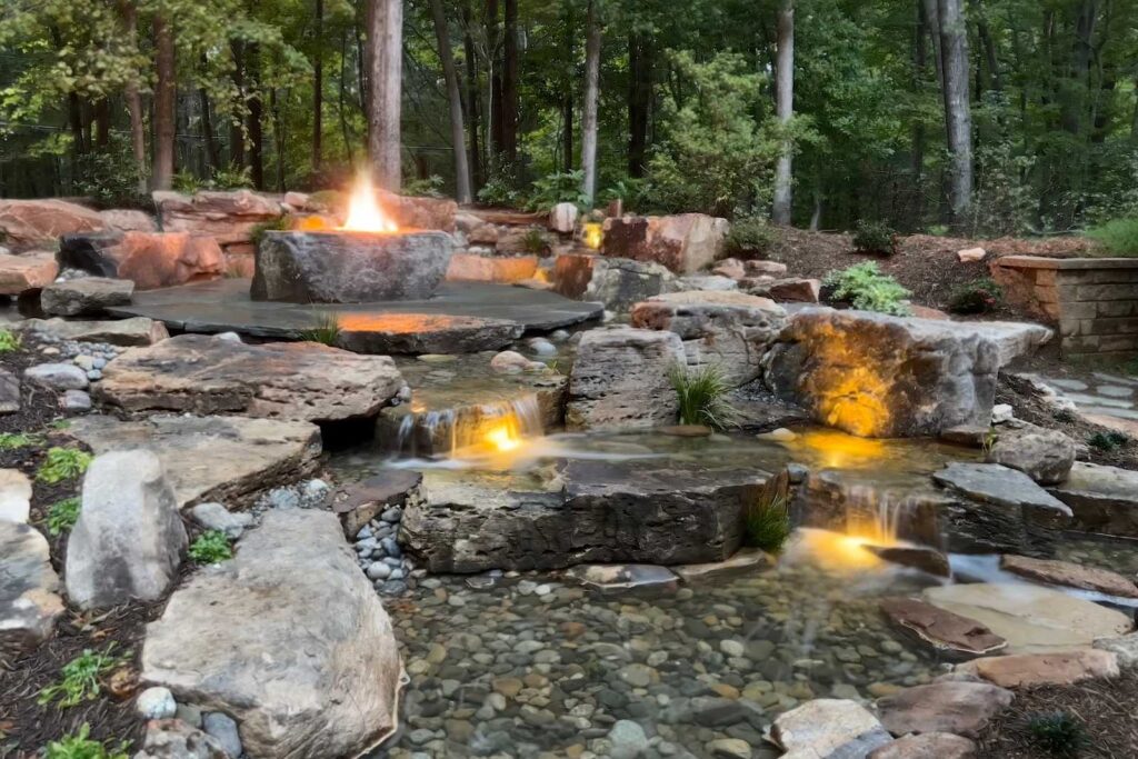 Custom fire boulder feature with natural stone waterfall and patio installation in Weddington, North Carolina, built by Pondscapes of Charlotte