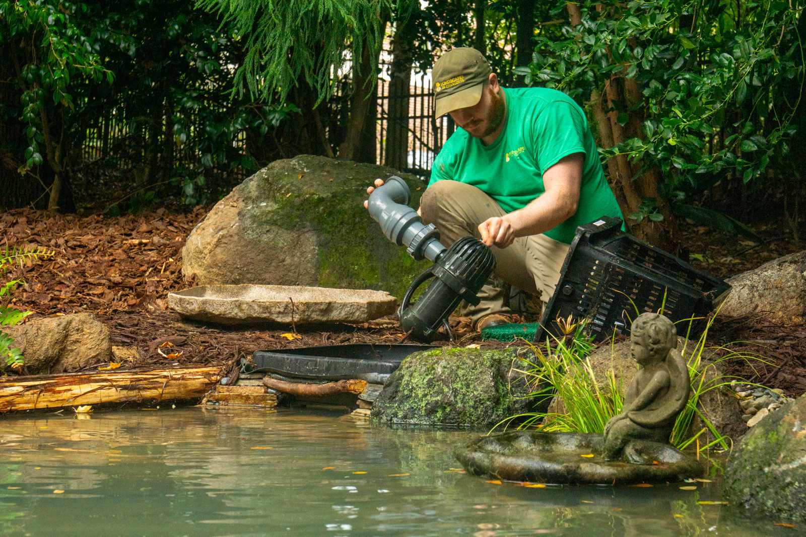 Pond technician installing pump and skimmer during backyard pond construction in Charlotte NC