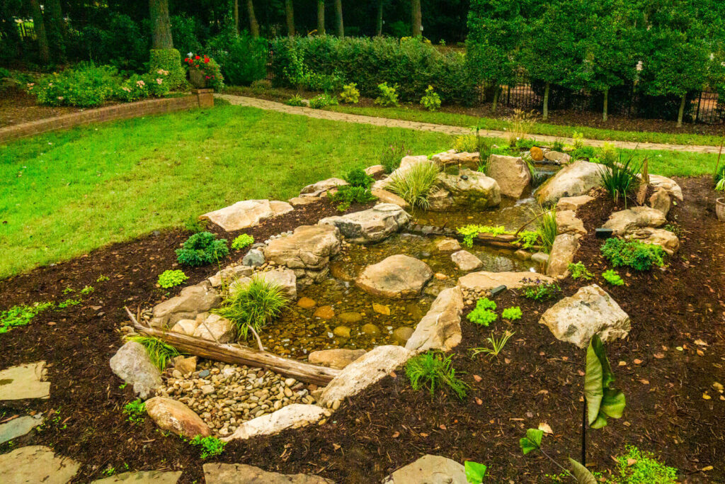 Overhead view of pondless waterfall stream with natural stone and cedar log in Marvin NC
