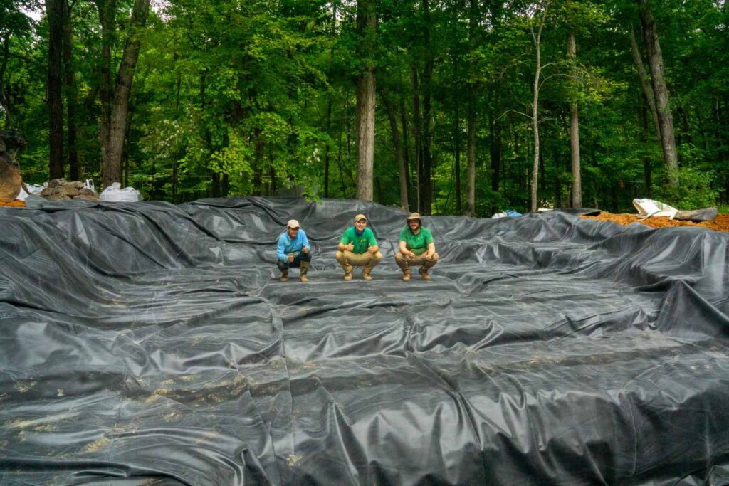 Pond installation crew on liner during waterfall construction in Weddington NC