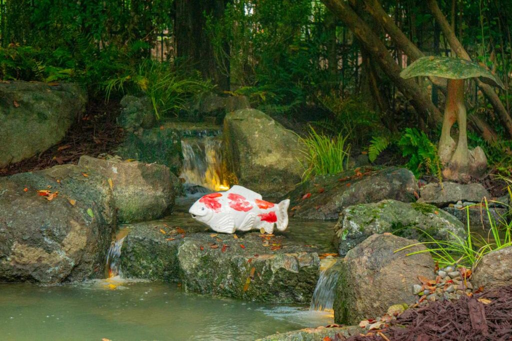 Koi pond with stone waterfall and decorative statue in South Park Charlotte NC backyard