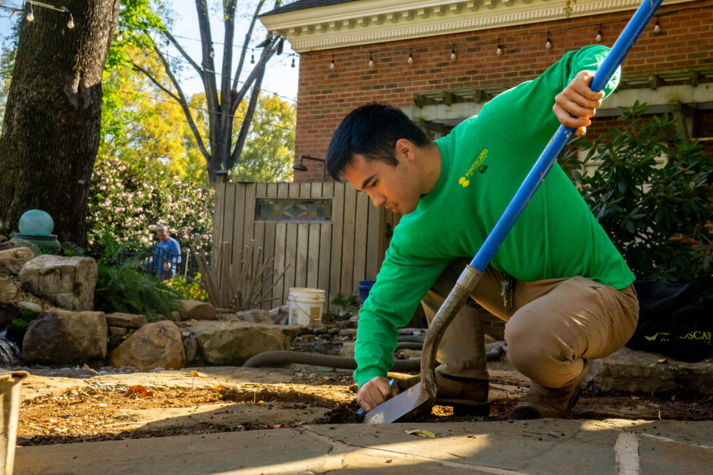 Pond builder excavating trench during backyard pond installation in South Park Charlotte NC