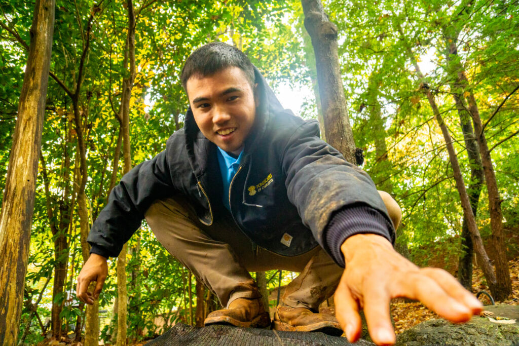 Technician removing leaves from pond net during monthly pond maintenance service in Charlotte NC