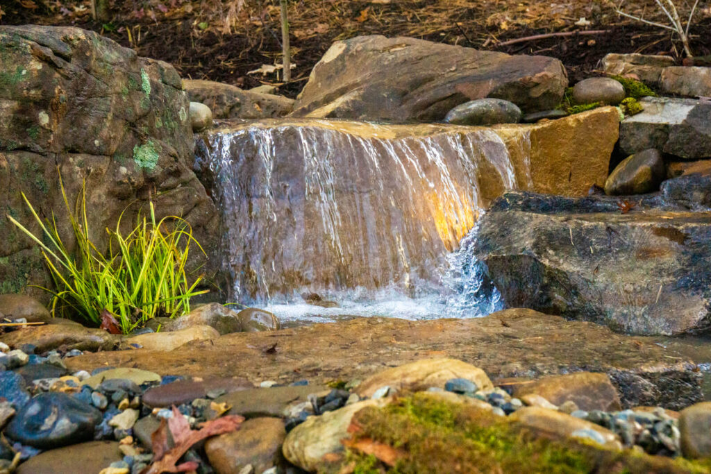 Stone pondless spillway with flowing water, underwater lights, and aquatic plants Fort Mill SC