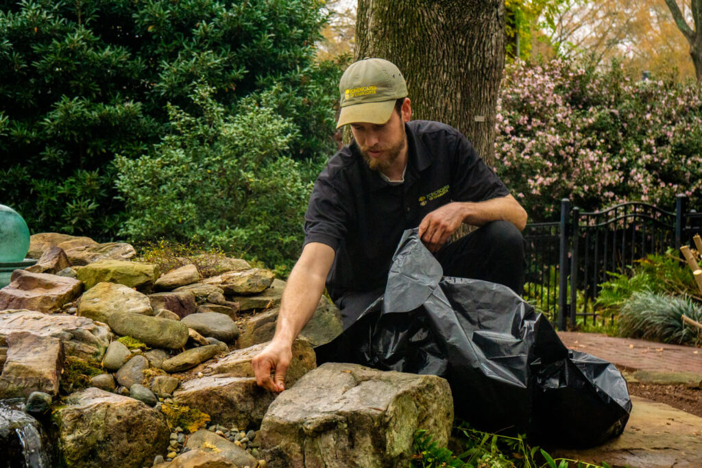 Water feature technician cleaning natural stone pond in South Park Charlotte, NC