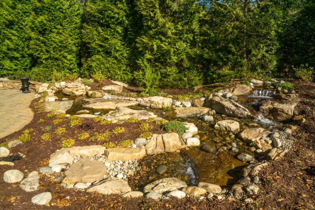 Backyard pondless waterfall installation with natural stone in the Kingsmead Kingsmead Neighborhood, Marvin NC