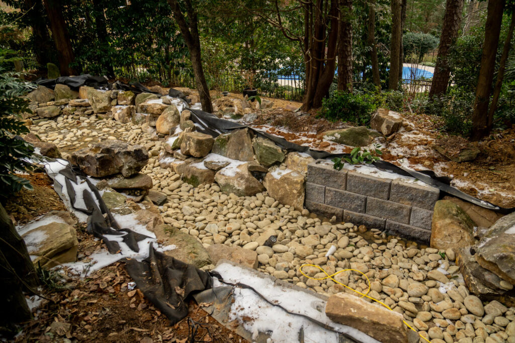 Backyard pond construction site with pond liner and stone in Matthews NC