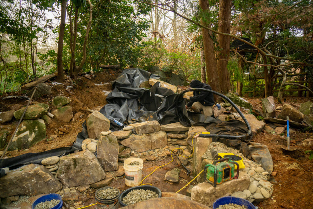Backyard pond construction in progress with liner and rocks in Matthews NC