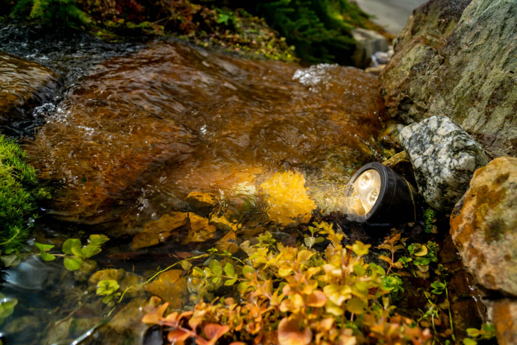 Underwater pond lighting illuminating waterfall during winter maintenance