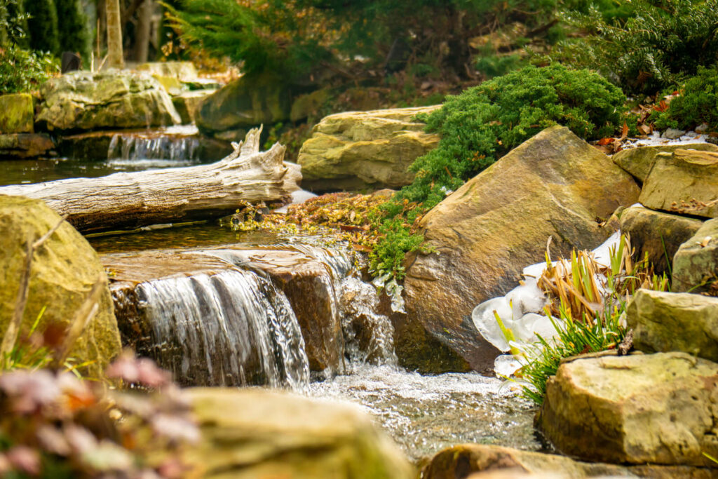 Natural waterfall with moss during winter pond service