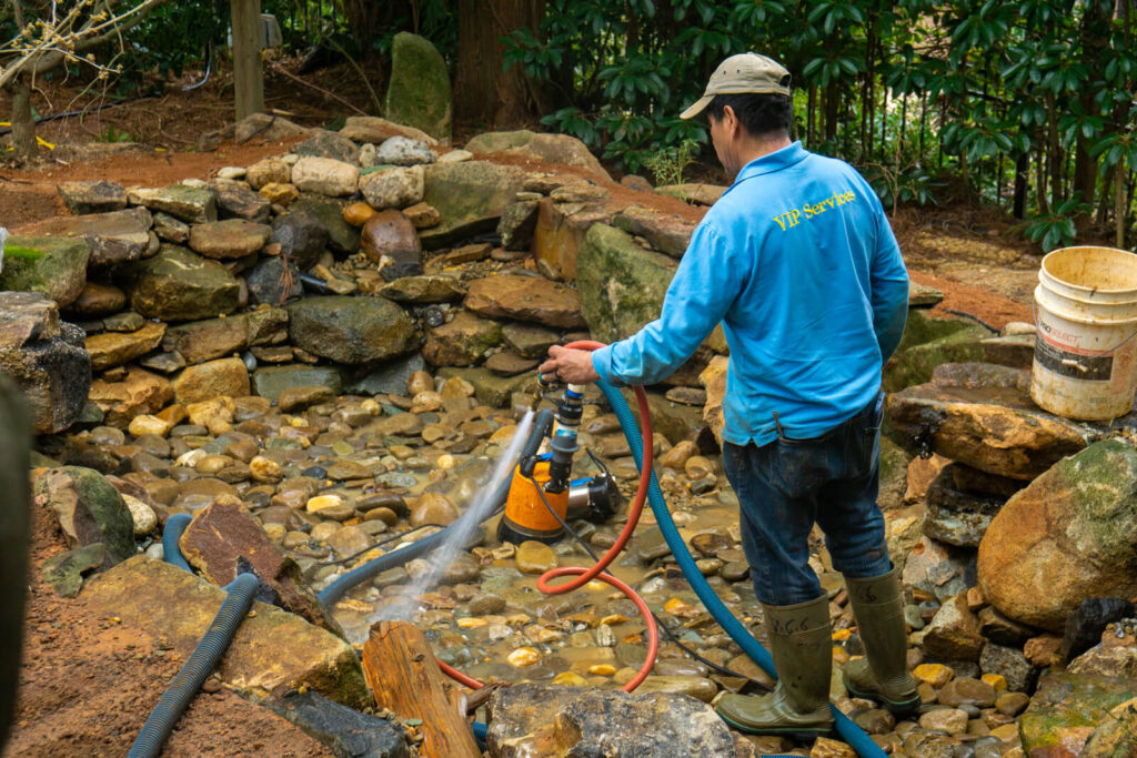 Pondscapes of Charlotte VIP technician pressure washing newly built stream pond Matthews NC