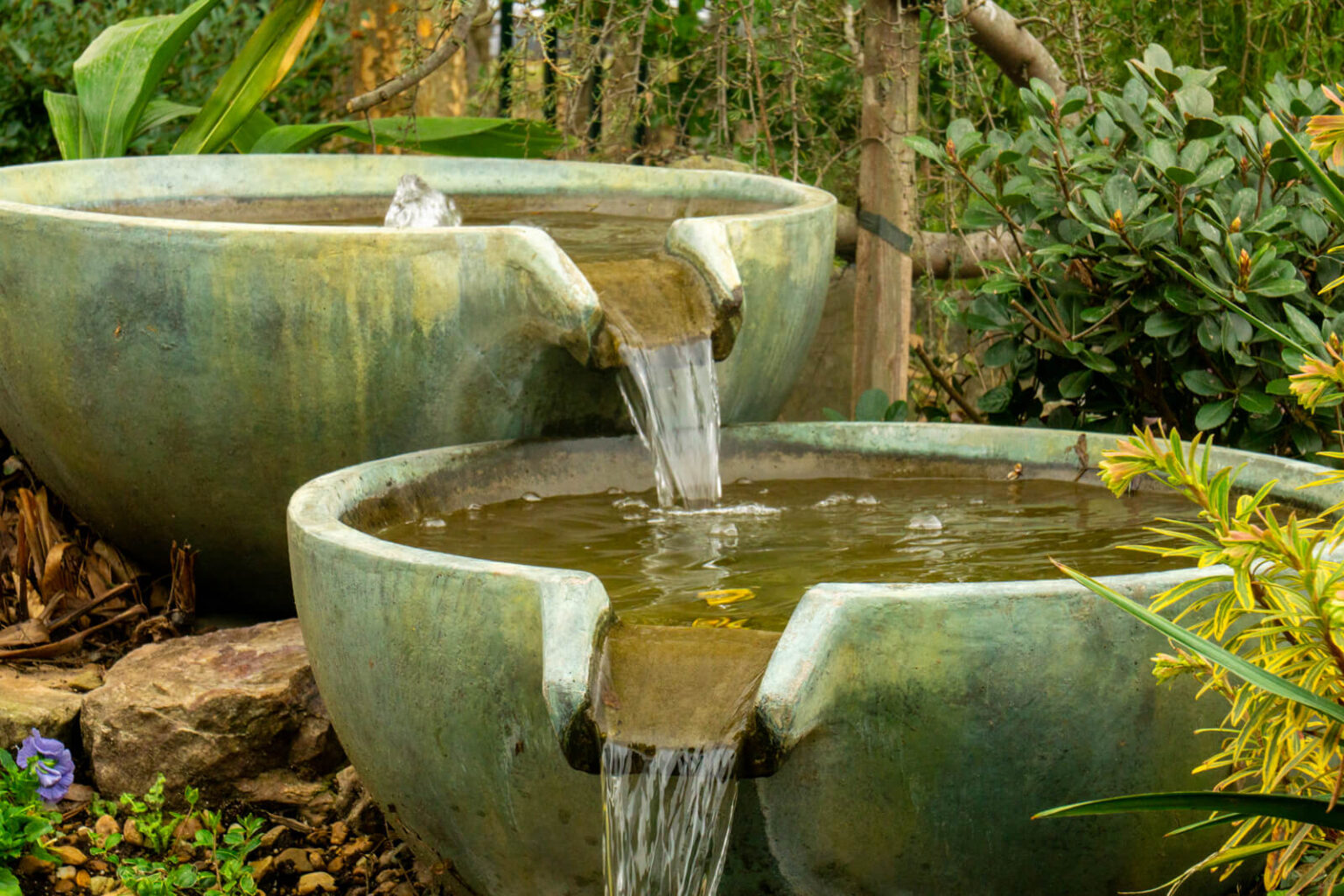Close up of tiered Aquascape Spillway Bowls next to a natural pond in Matthews, NC