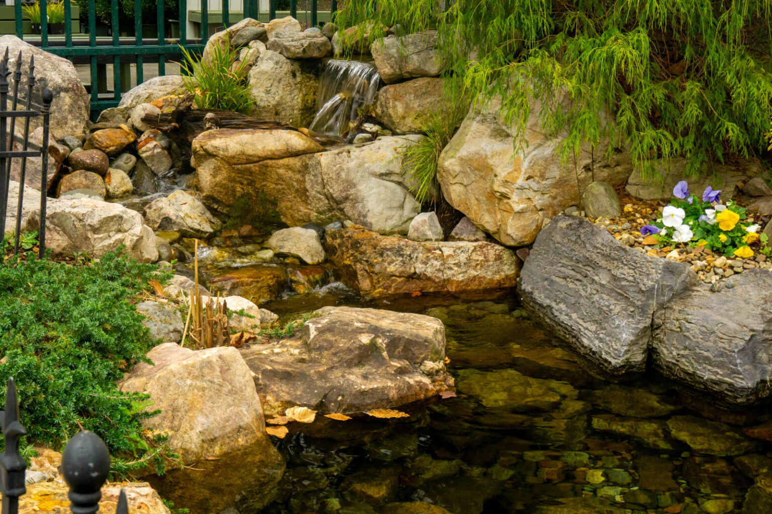 Natural stone waterfall and ecosystem pond with aquatic, annual, and perennial plants at Pike Nurseries Matthews, NC
