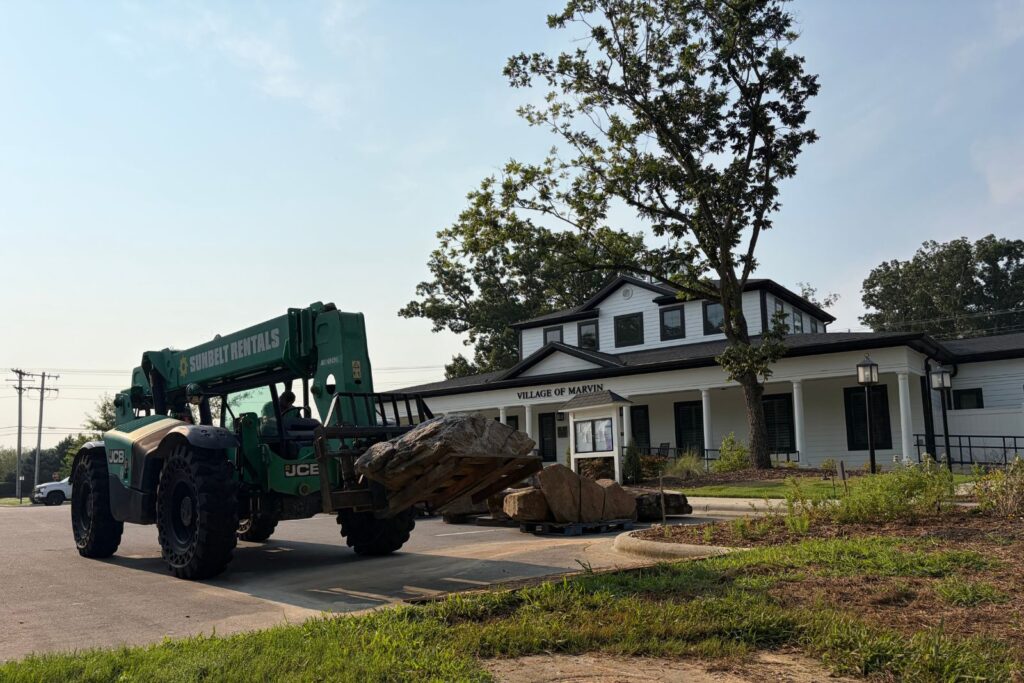 Excavator moving boulder for new water feature in Marvin, NC