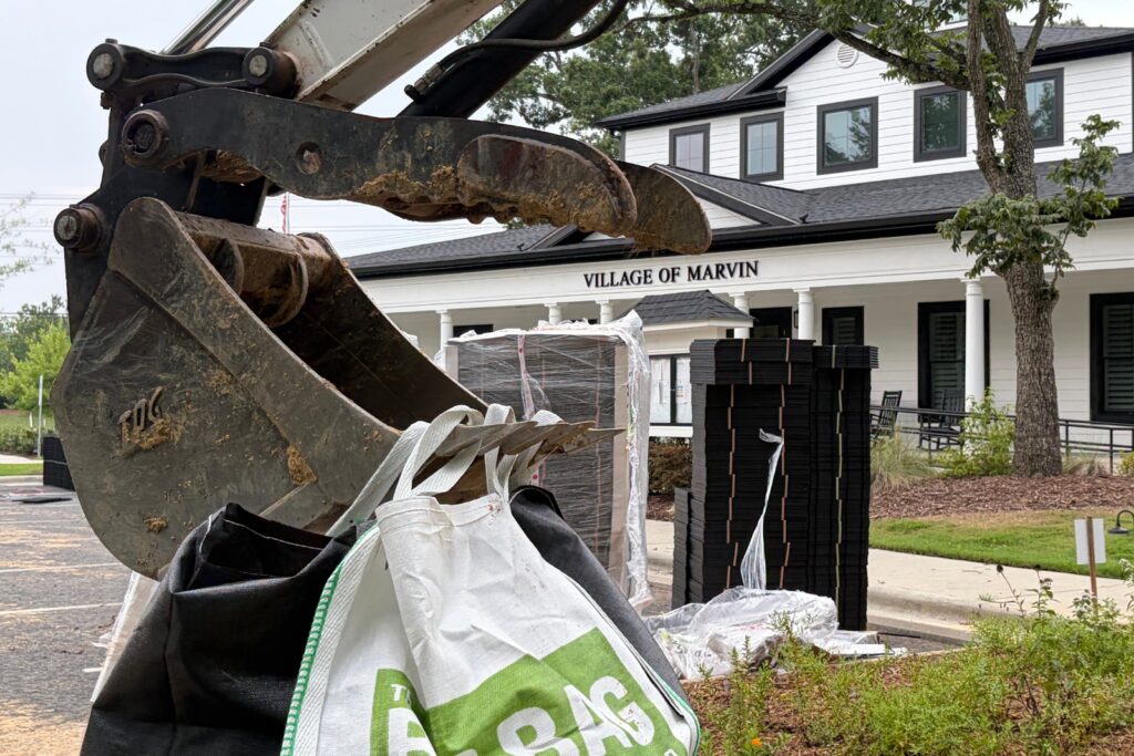 Excavator caring bag of rocks to the jobsite in Marvin, NC.