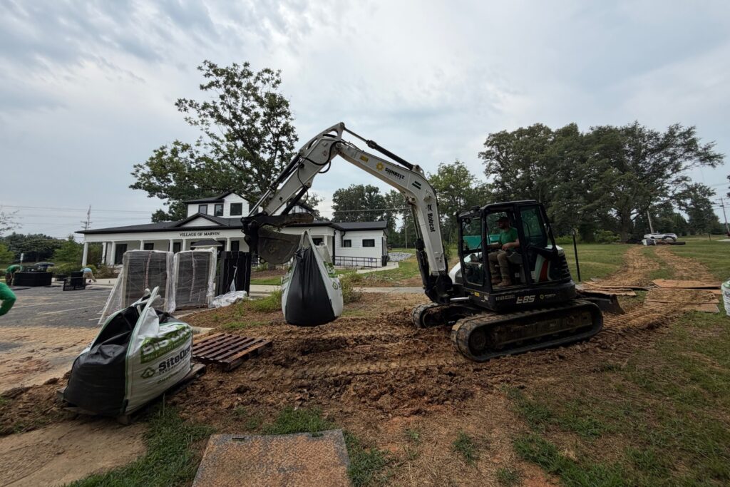 Bags of rocks being positioned on site in Marvin, NC using excavator.