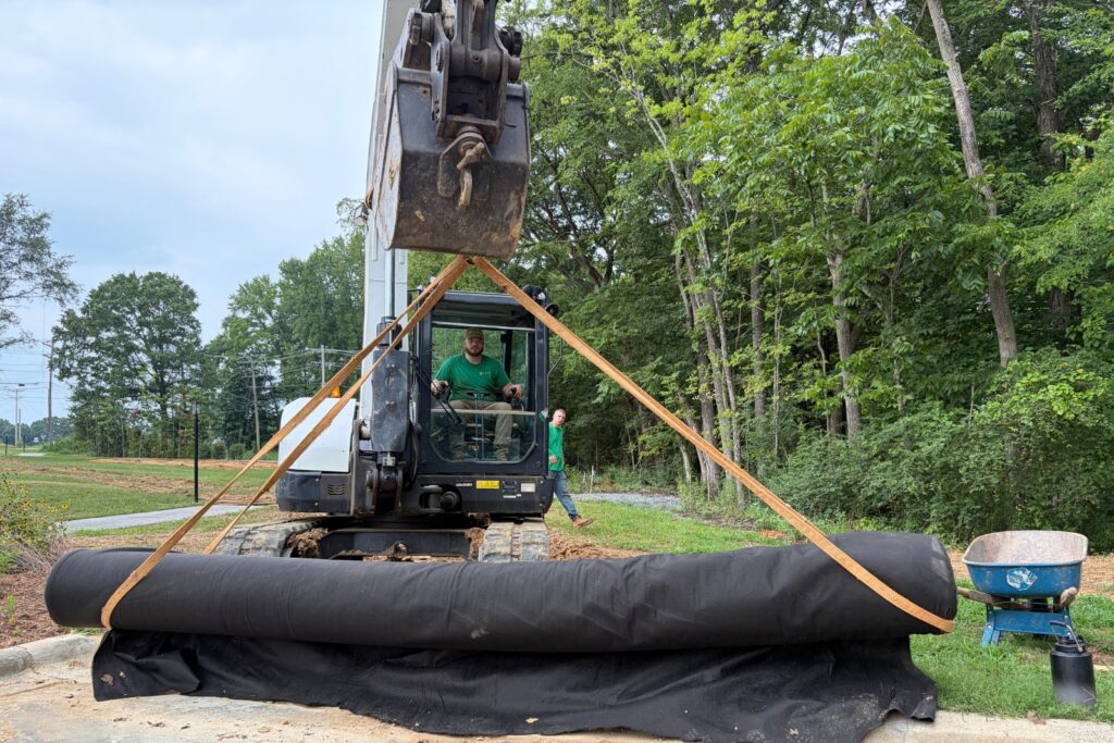 Excavator bringing new liner to be installed in new rainwater harvesting system.