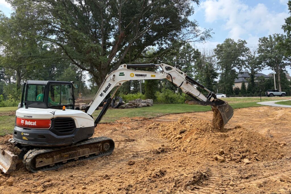Excavator moving dirt on site for new water feature project in Marvin, NC.