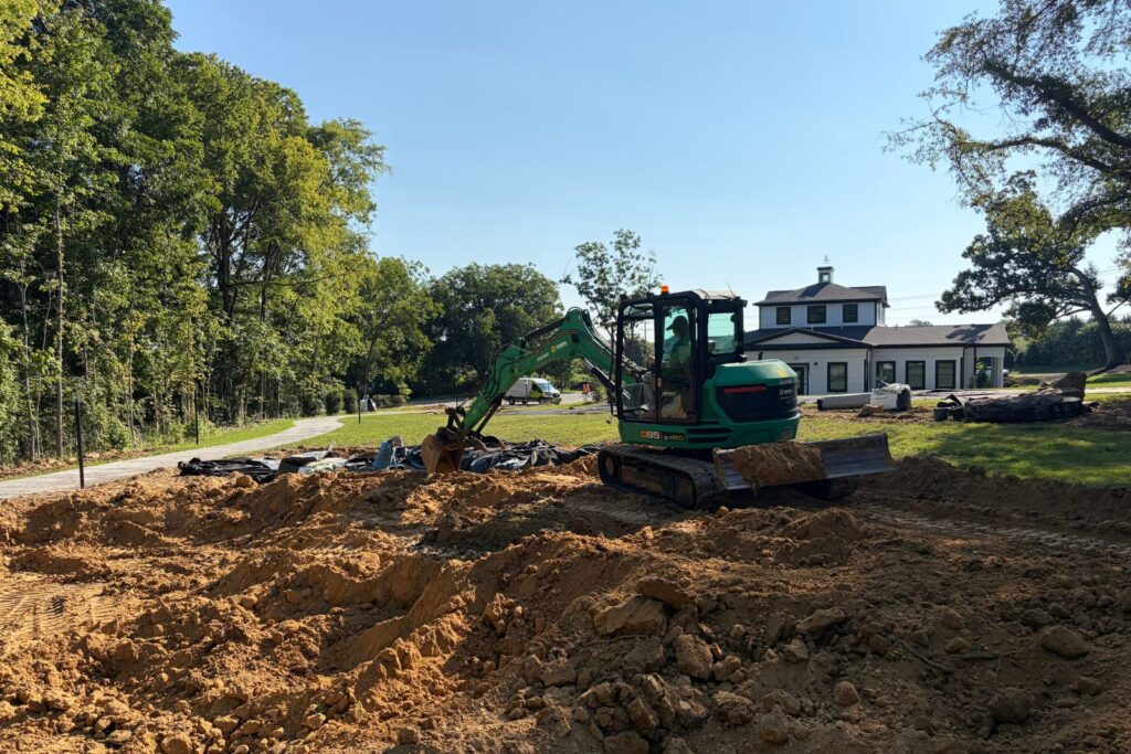 Excavator moving dirt on the jobsite for new water feature install.