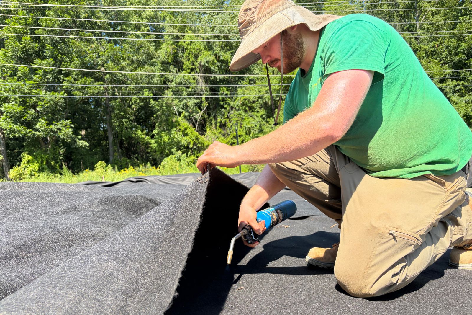 Crew member using a handheld heat tool to secure overlapping sections of the liner.