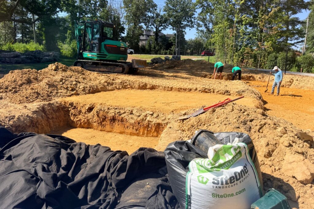 Construction site with an excavator and crew members leveling the ground.